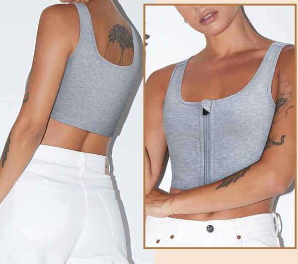 A person is wearing a light gray ftm chest binder with a zipper on the front and white pants. The image shows both the back and front views of the outfit. The person has tattoos on their arms and one on their shoulder blade.