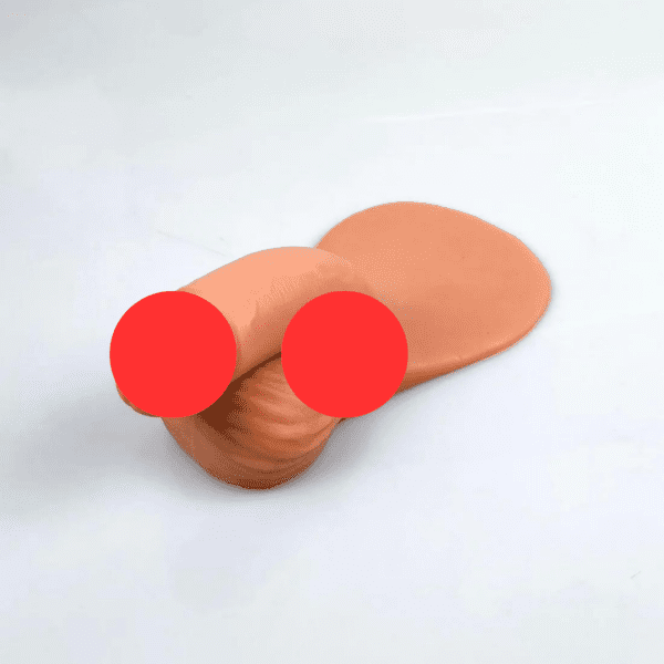 A skin-toned, ivory & beige p*nis with two red circles overlies a shiny, smooth surface. The object appears to have a semi-cylindrical, folded section resting on a flattened part. The background is plain and white.