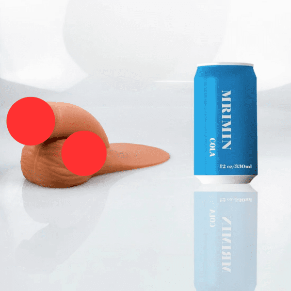 A blue can labeled "MRMIMI COLA" stands upright on a glossy white surface. To the left, a light brown, elongated squishy object resembling a cheap soft packer is placed, with two red circles obscuring parts of it. The can's reflection is visible on the surface.