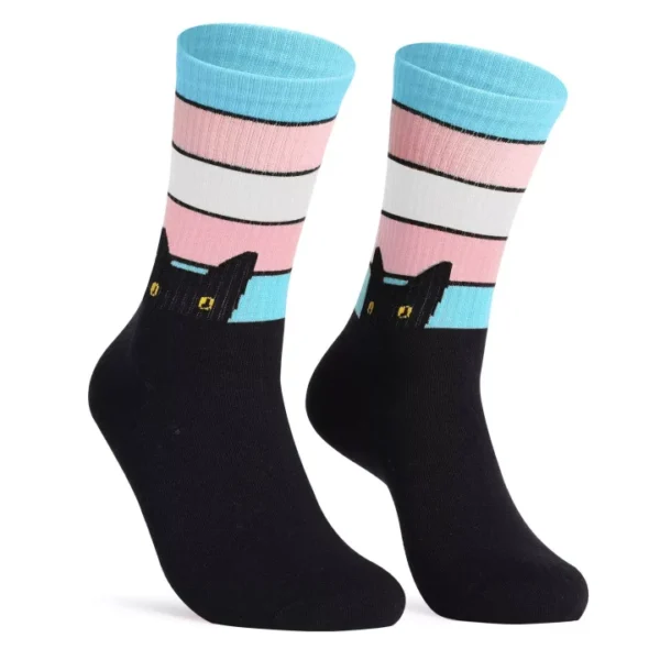 A pair of colorful trans flag socks featuring a design with black cat faces. The upper part of the socks has horizontal stripes in blue, white, and pink, representing the transgender pride flag. The lower part is solid black with cat faces peeking over.