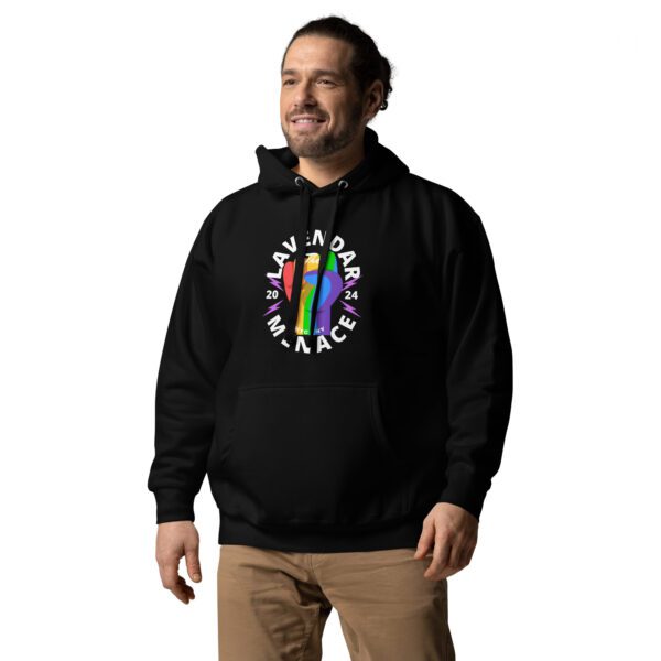 A person with a beard and ponytail smiles while wearing a black Unisex Hoodie featuring a vibrant graphic and the text "Lavender Menace 2024." Paired with beige pants, they stand confidently against a plain background.